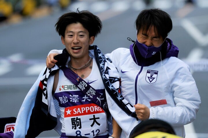 10区で大逆転を演じトップでゴールテープを切った駒澤の石川（左）と、出迎えた主将の神戸（右）。写真：JMPA