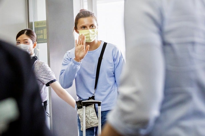 羽田空港で関係者やメディアに手を振るツィマノウスカヤ。ポーランドで夫と再会を果たす予定だ。(C)Getty Images