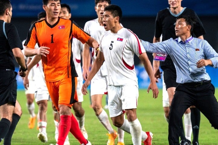 試合後、主審に激昂して詰め寄る北朝鮮の選手（中央）を制止しようとする監督（右）。世界中に波紋が広がっている。(C)AP/AFLO