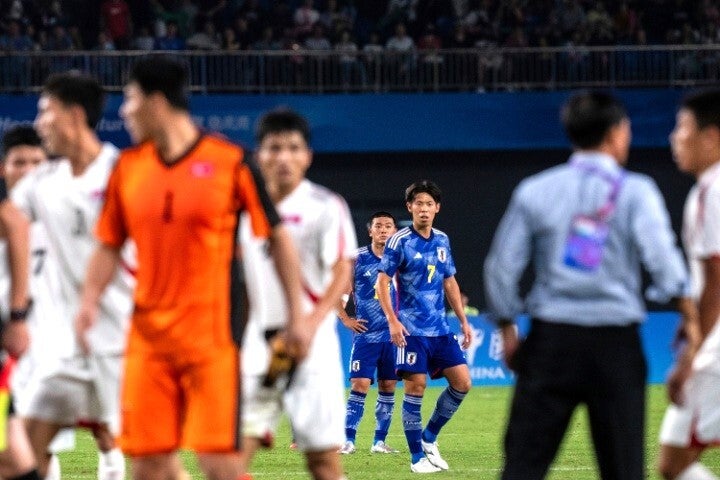 試合後、北朝鮮の選手（手前）が審判に詰め寄る様子を啞然と見る日本代表（奥）の選手たち。(C)AP/AFLO