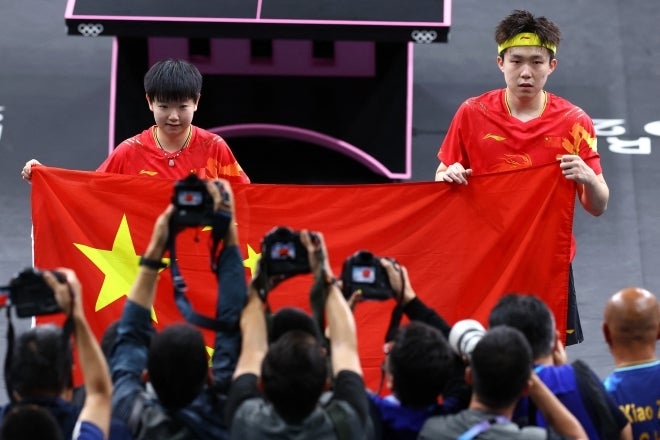 優勝を決めて国旗を掲げる中国ペア。まさにこの瞬間、ラケットが破壊されたとみられる。(C)REUTERS/AFLO