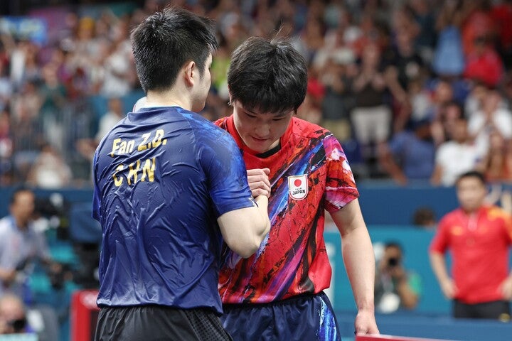 がっちりと握手を交わす張本智和（右）と樊振東（左）。(C) Getty Images