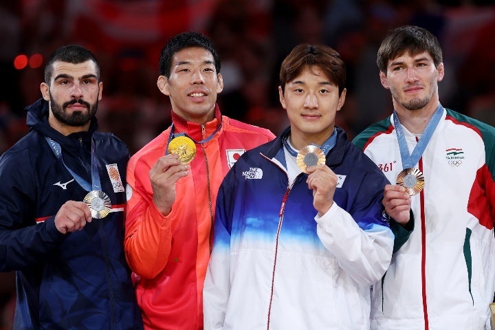 パリ五輪の表彰式では金メダリストにもかかわらず、永瀬（左から２人目）は控え目な位置に立っていた。(C) Getty Images