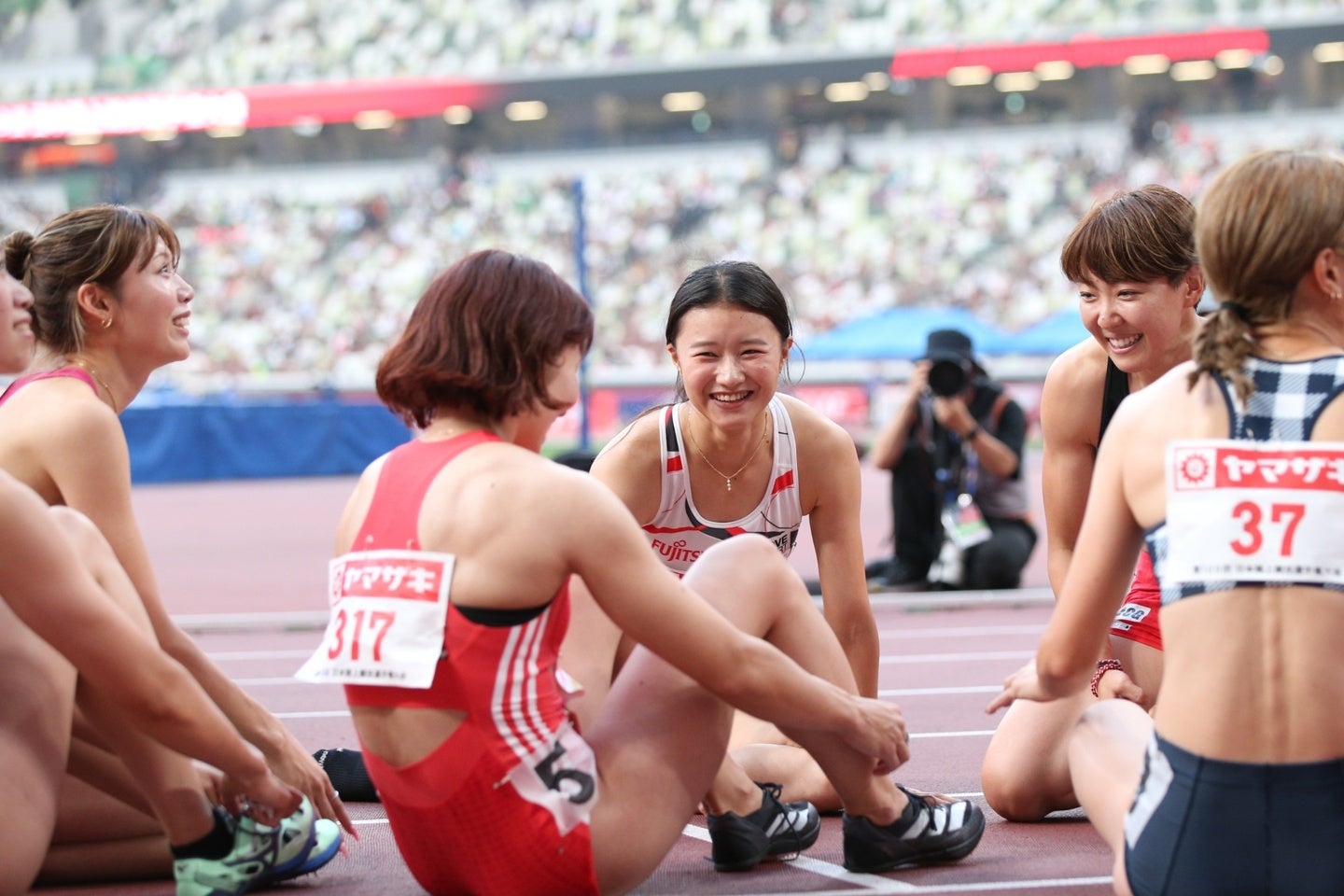 中央は田中佑美。順位が確定する間、８人全員がトラックで座りながら結果を待った。写真：永島裕基