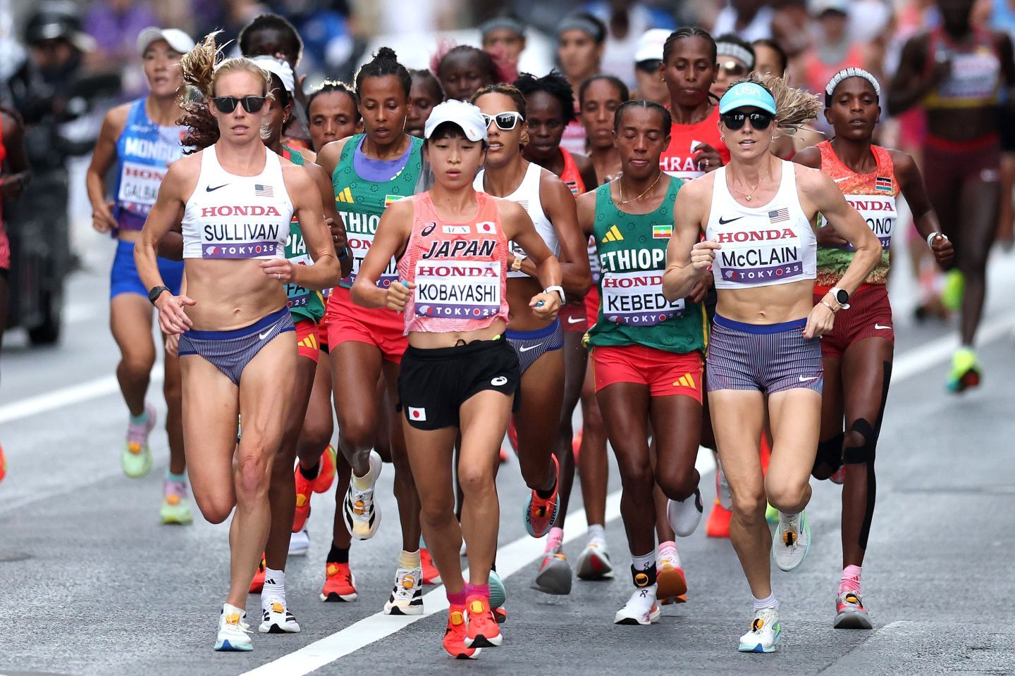 先頭の小林（中央）を挟むように、白いウェアのアメリカ代表２選手が並走する。(C)Getty Images