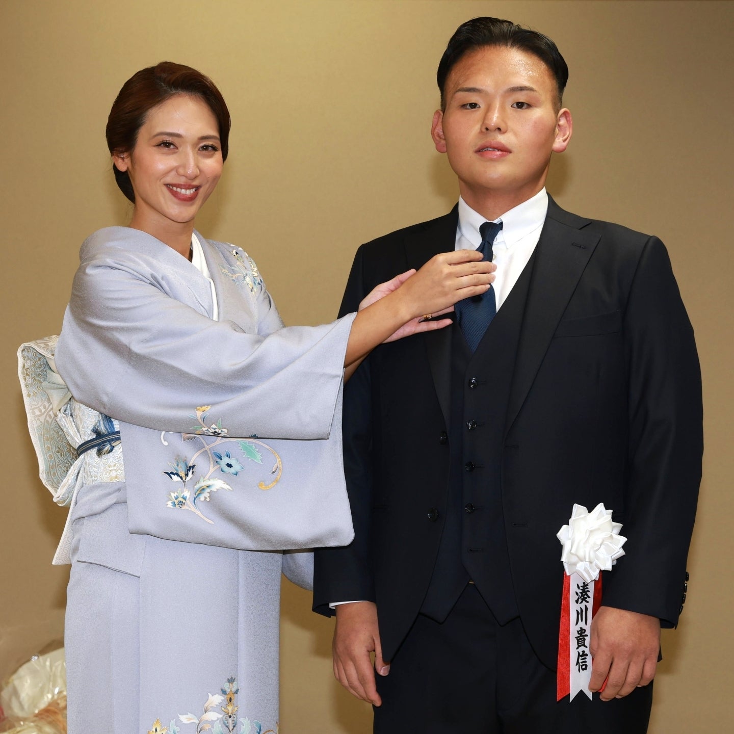 断髪式を終えた湊川親方（貴景勝）のネクタイを整える有希奈夫人。今月中旬に第２子を出産予定と明かされた。写真：産経新聞社