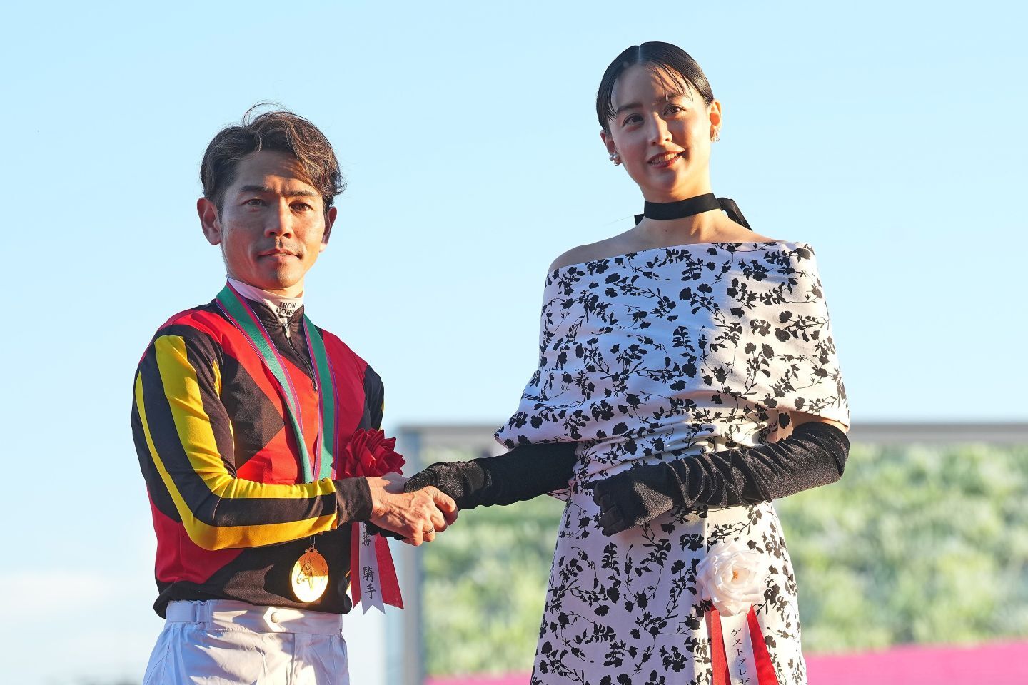 勝利ジョッキーの戸崎圭太と握手を交わすプレゼンターの山本美月さん。写真：産経新聞社